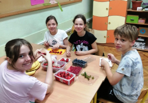 Uczniowie siedzą przy stole i przygotowują zdrową żywność